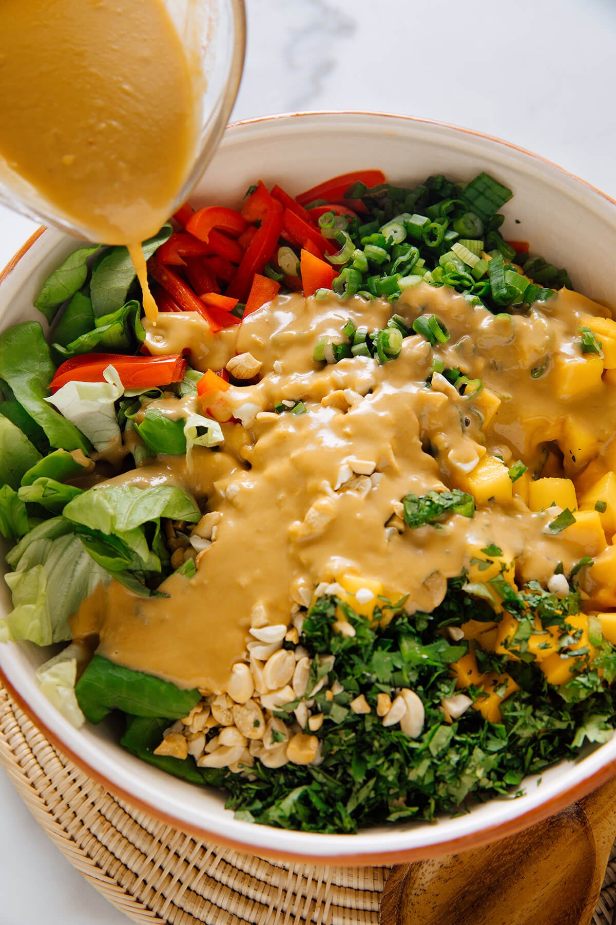 pouring dressing over mango salad