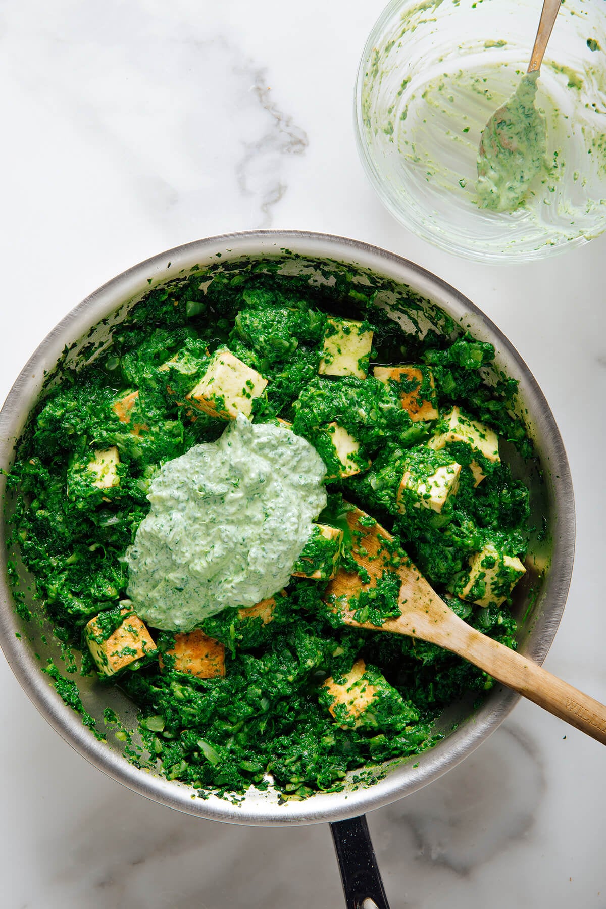 stirring tempered yogurt into palak paneer